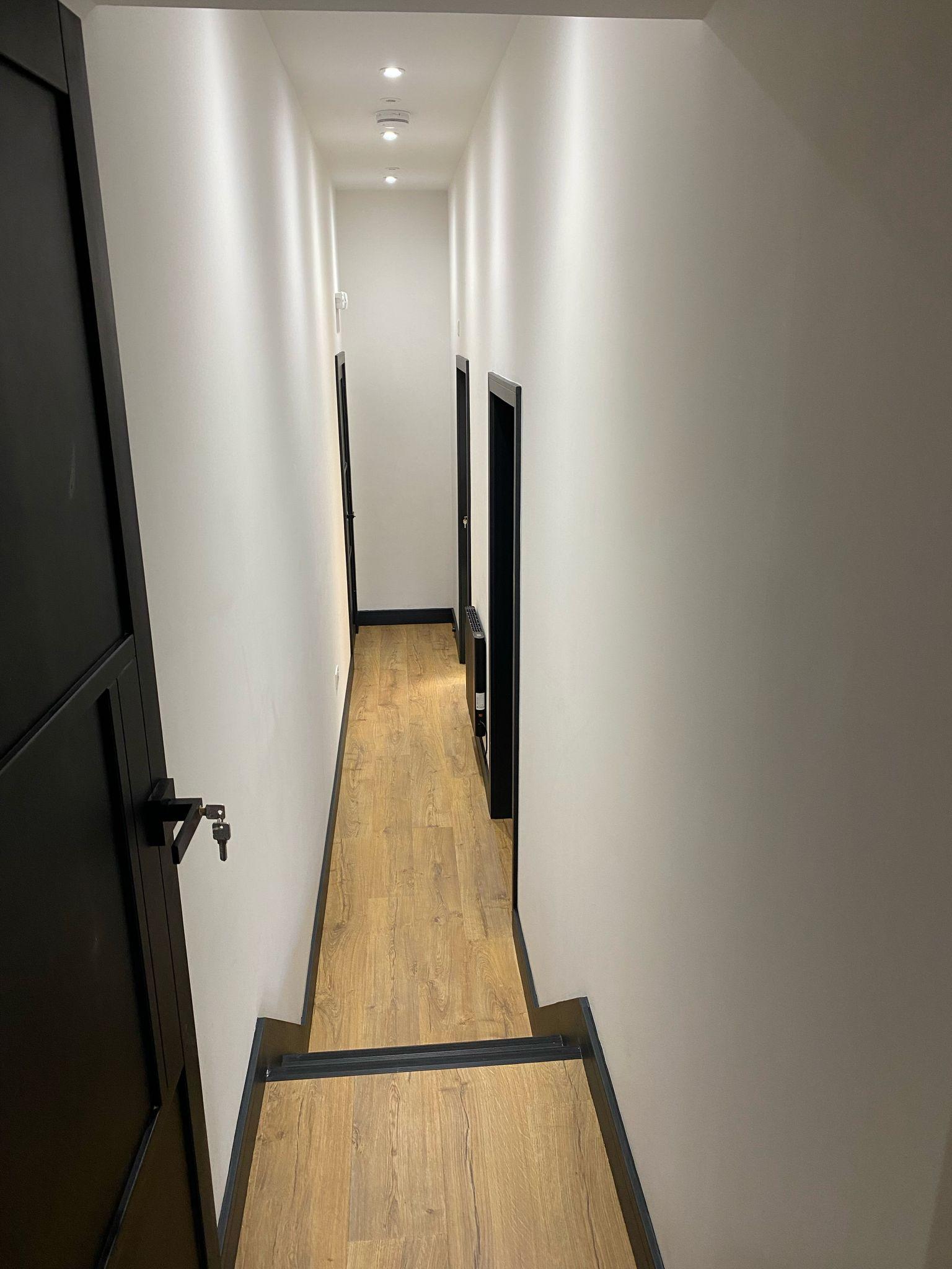 Finished hallway with oak flooring and dark doors